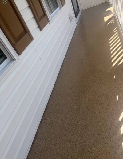 A porch featuring a white fence and a brown concrete floor, creating a welcoming outdoor space - after