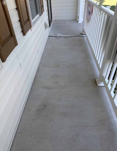 A porch featuring a white fence and a brown concrete floor, creating a welcoming outdoor space - before
